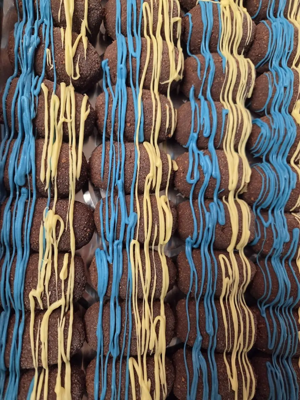 A tray of kartoshka cakes drizzled with blue and yellow icing.